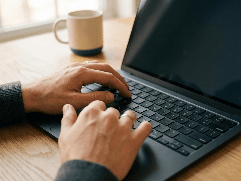 Close-up of hands typing on a MacBook keyboard in warm natural light