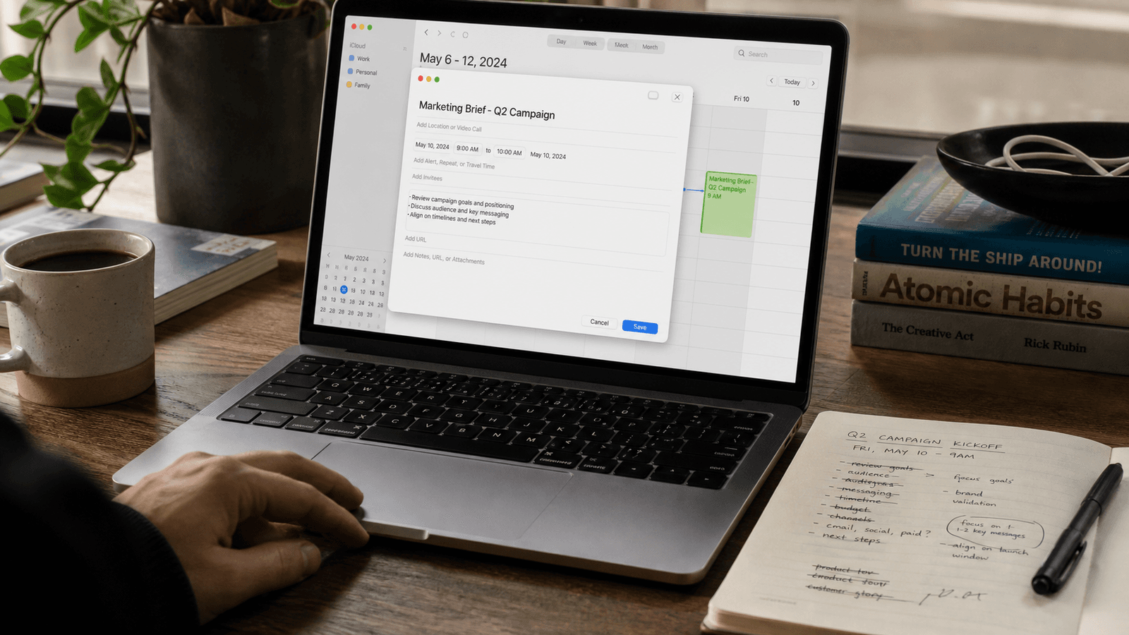 Calendar invite being written on a MacBook with agenda notes beside it